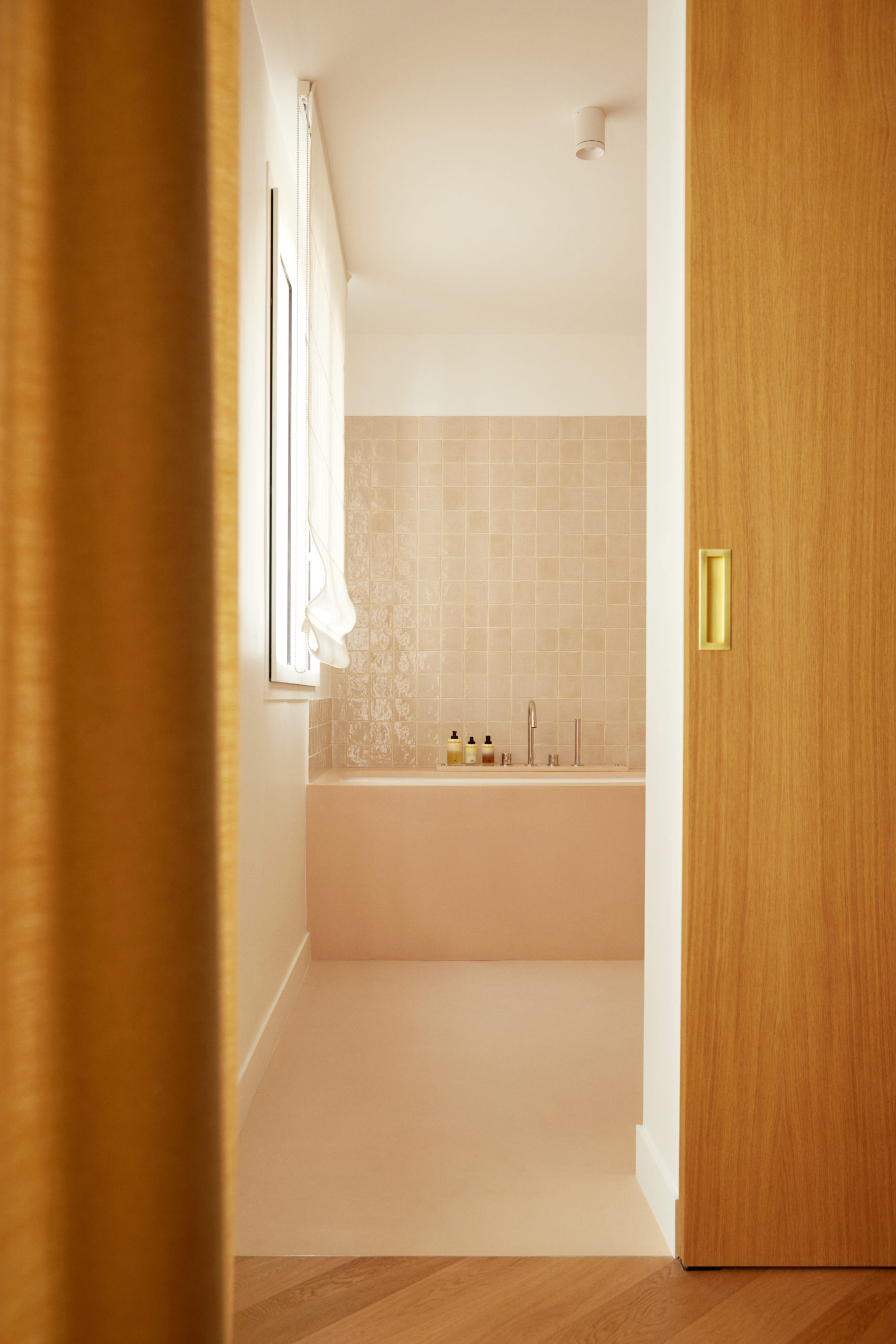 Salle de bain en béton ciré et zellige vue depuis la chambre - Store bateau en lin blanc - Porte en chêne poignée cuvette laiton