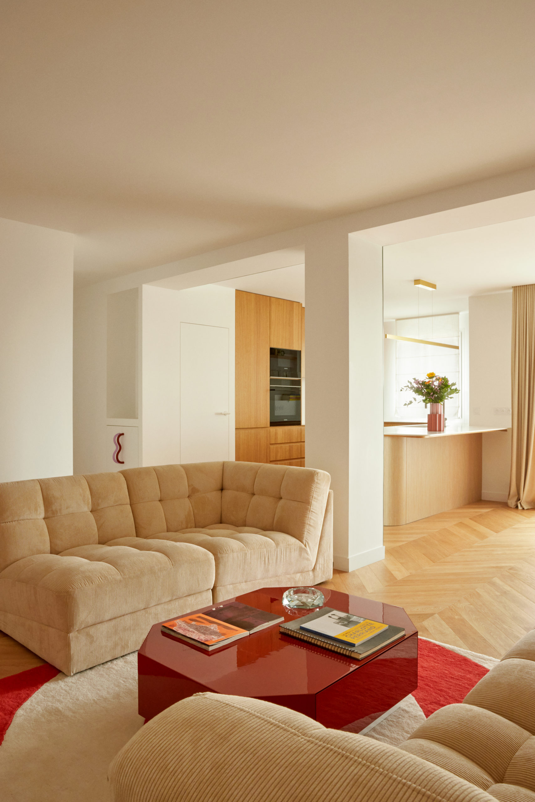 Rénovation d'un appartement - Salon avec deux canapé en velours côtelé beige , table basse laqué rouge socialite familly , vue vers la cuisine et l'entrée - Poignée de placard en verre Sabourin Coste - Parquet en chêne pose point de hongrie