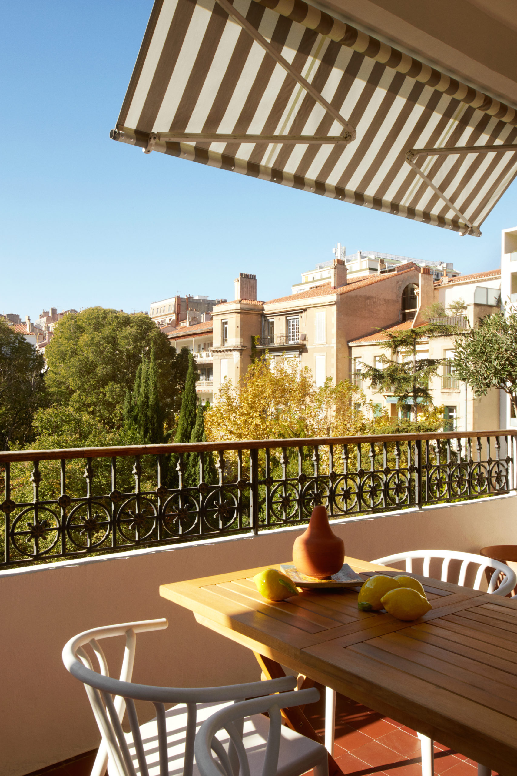 Loggia avec table repas et store banne donnant sur un jardin arboré