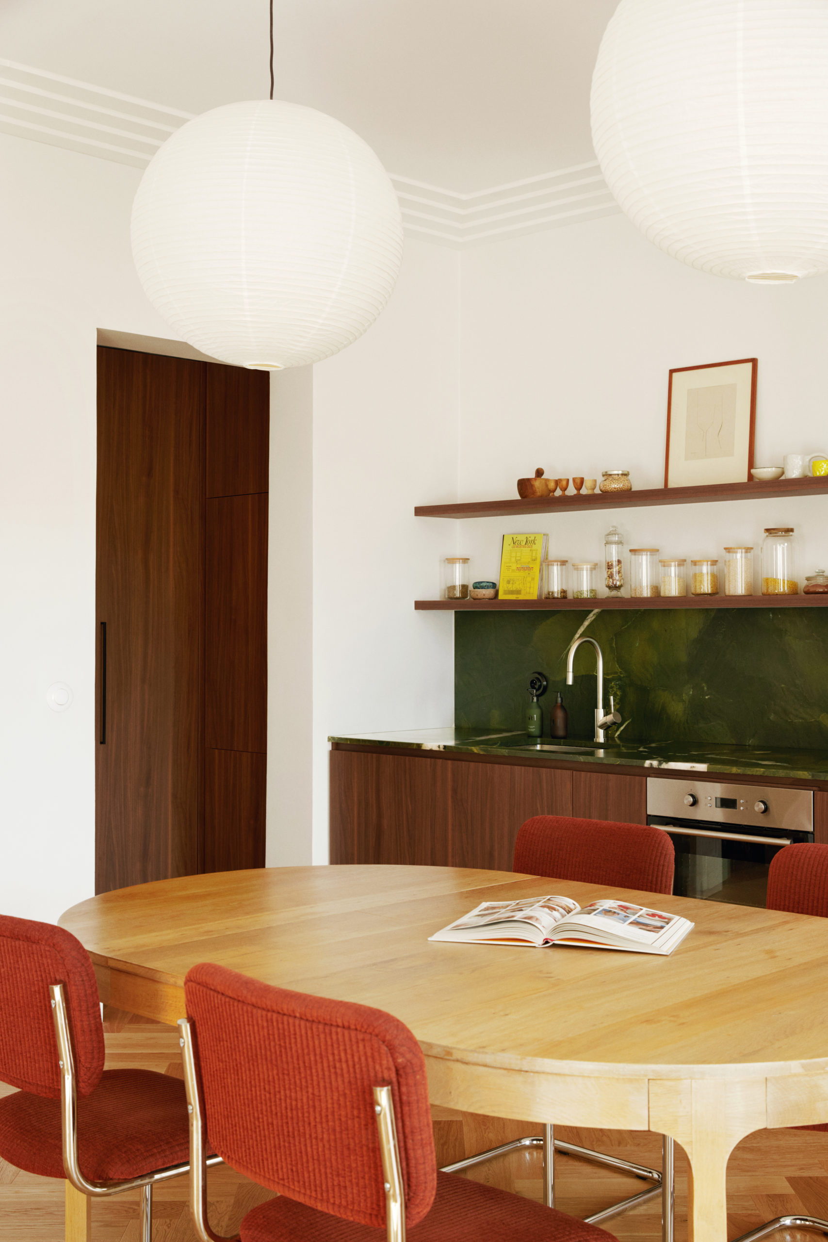 Une parti de la table à manger, la cuisine et l'arrière cuisine avec un livre de cuisine ouvert sur la table