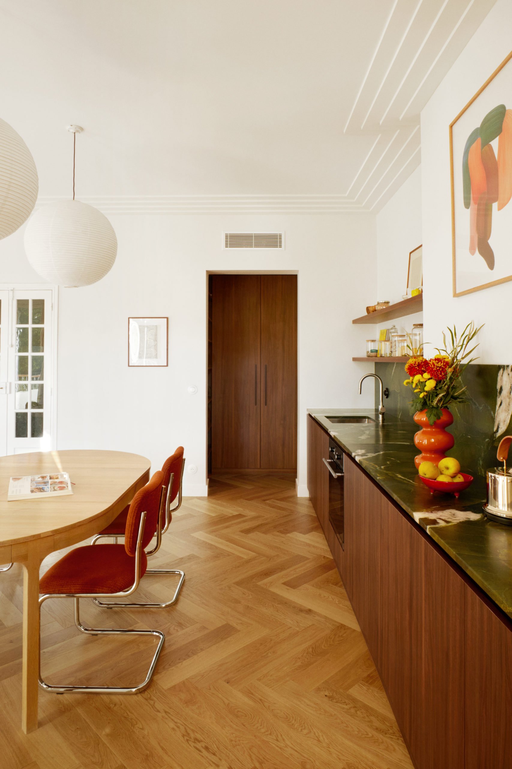 Vue de ka cuisine et de la salle à manger vers le cellier. En fond, la porte conservé en bois et petits carreaux de verre et une sérigraphie de la fondation Vazarely