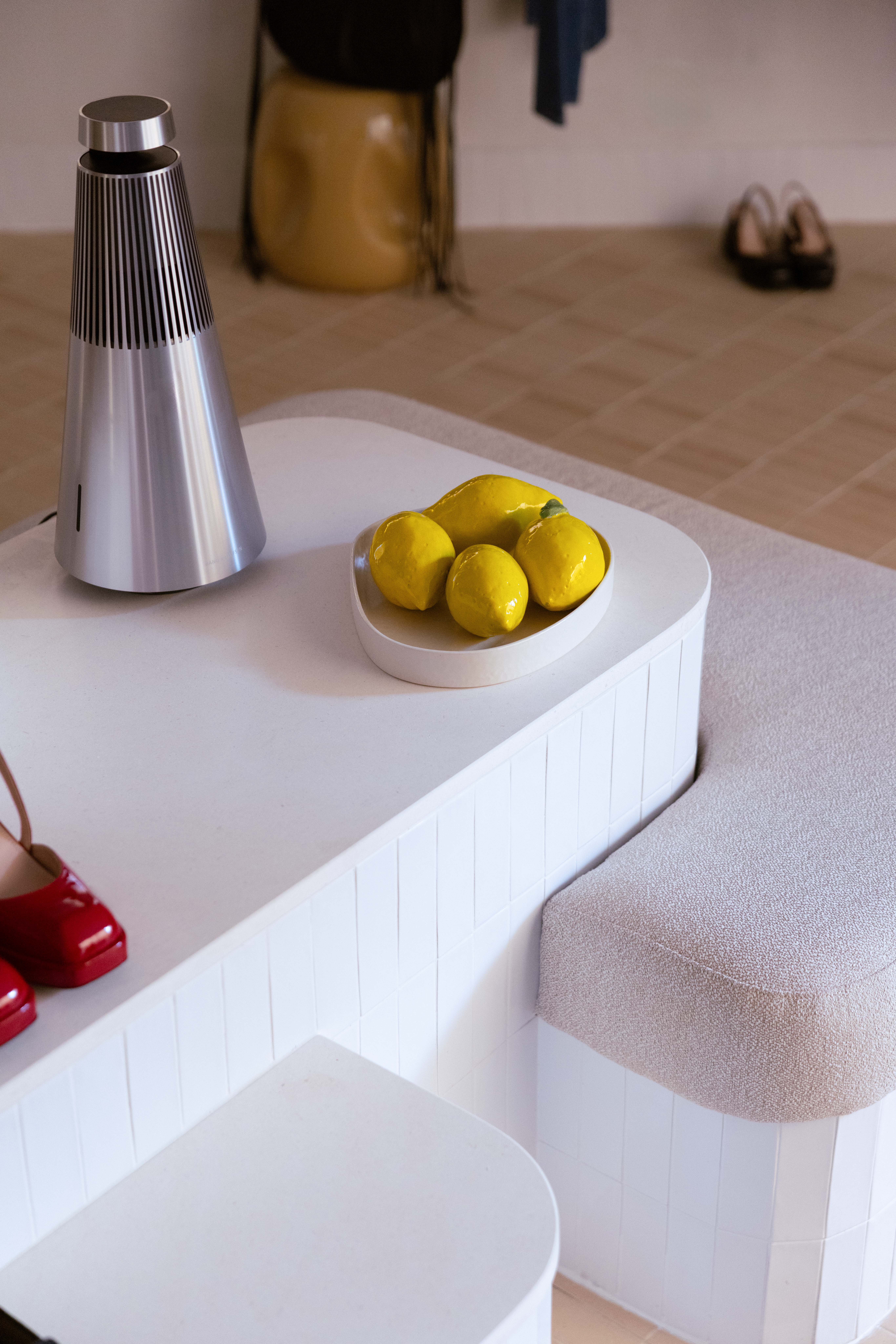 Vue détaillé de l'ilot avec sa banquette en tissus. On voit l'enceinte en inox et les citrons en céramique Argile et Clémentine