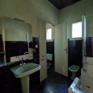 Salle de bain ancienne avec des carreaux noirs, un lavabo et une baignoire.