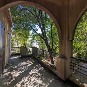 Arcade ombragée avec vue sur un jardin verdoyant et des arbres.