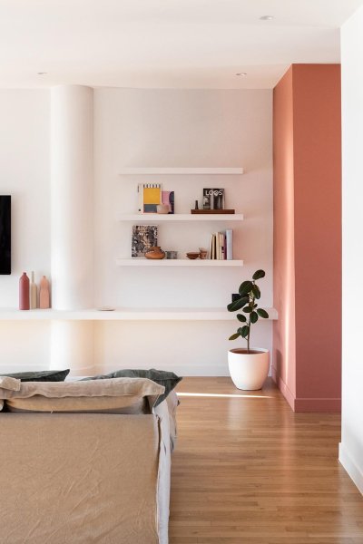 Intérieur moderne et lumineux avec canapé, étagères et télévision.