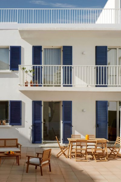 Belle terrasse avec mobilier de jardin devant un immeuble blanc et bleu.