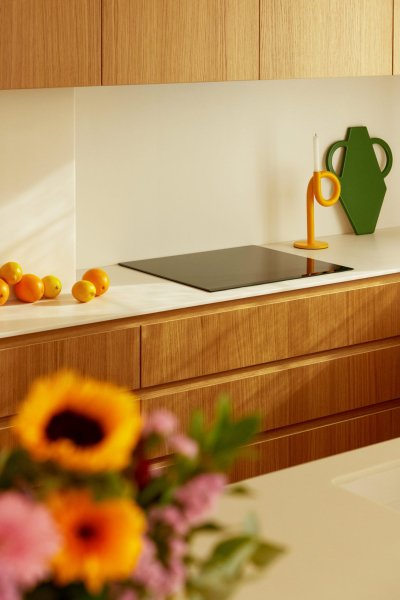 Cuisine moderne avec des oranges, un vase vert et un éclairage chaleureux.