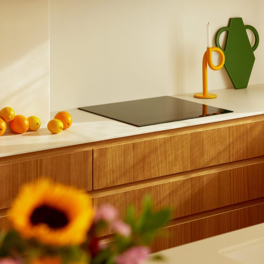 Cuisine moderne avec des oranges, un vase vert et un éclairage chaleureux.