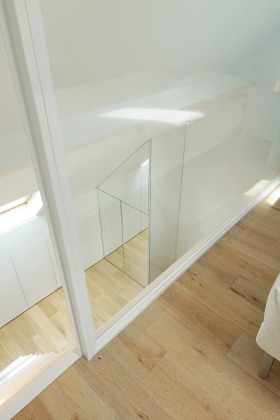 Une chambre d'étage lumineuse avec un miroir et un lit blanc.